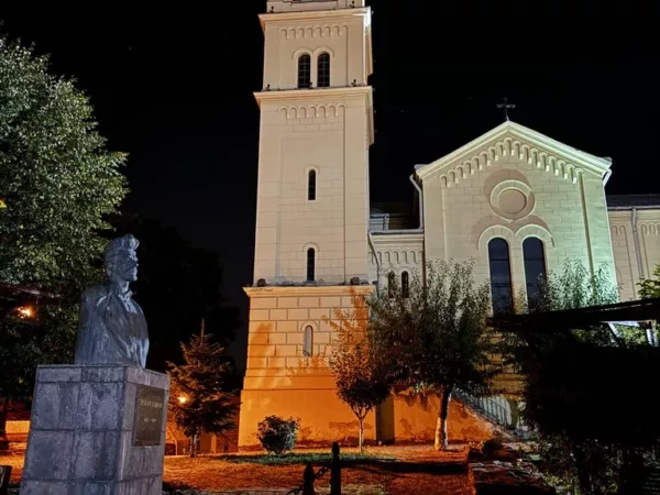 A church at night with a statue in front of it.