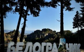 Vista panoramica delle formazioni rocciose di Belogradchik in Bulgaria, con la scritta in cirillico in primo piano tra gli alberi