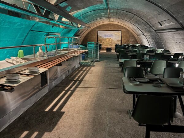 Interno della mensa del bunker antiatomico con tavoli, sedie e banconi originali in stile anni '60.