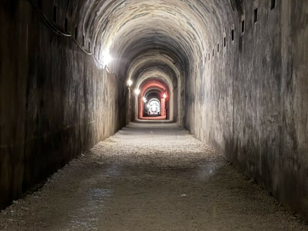 Veduta prospettica di una lunga galleria in cemento armato con illuminazione artificiale.